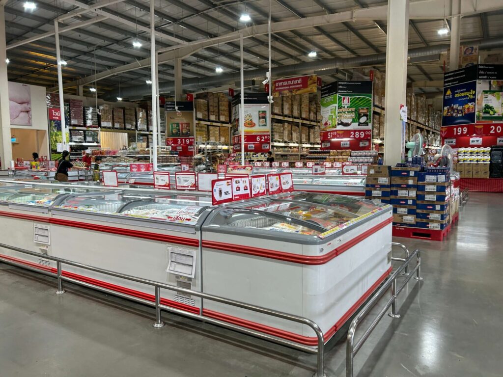 A long aisle of large freezers and bulk product shelving inside the wholesale supermarket Makro.