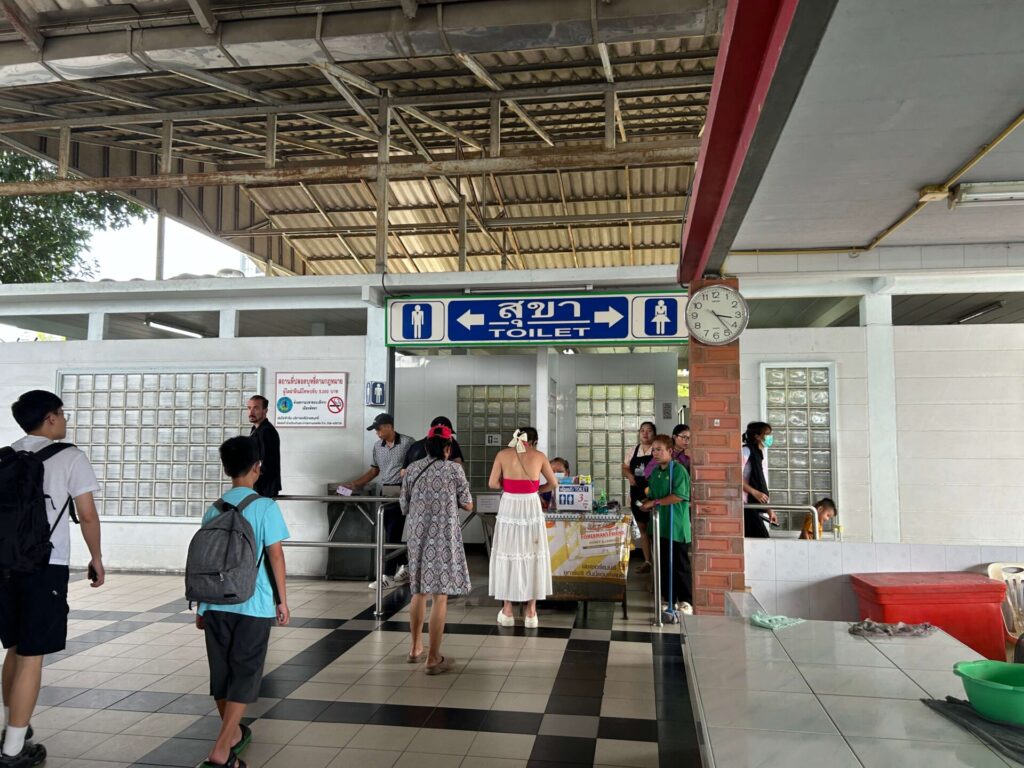 Sign pointing to restrooms (toilet) at North Pattaya Bus Terminal, with people nearby