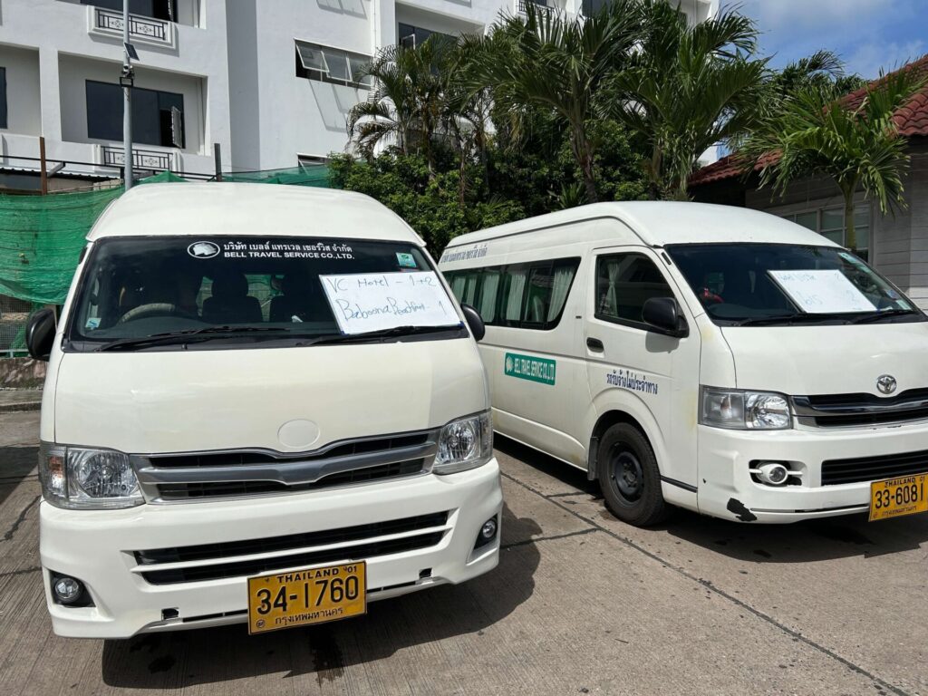 Two white Bell Travel Service minivans parked with signs indicating destinations or services