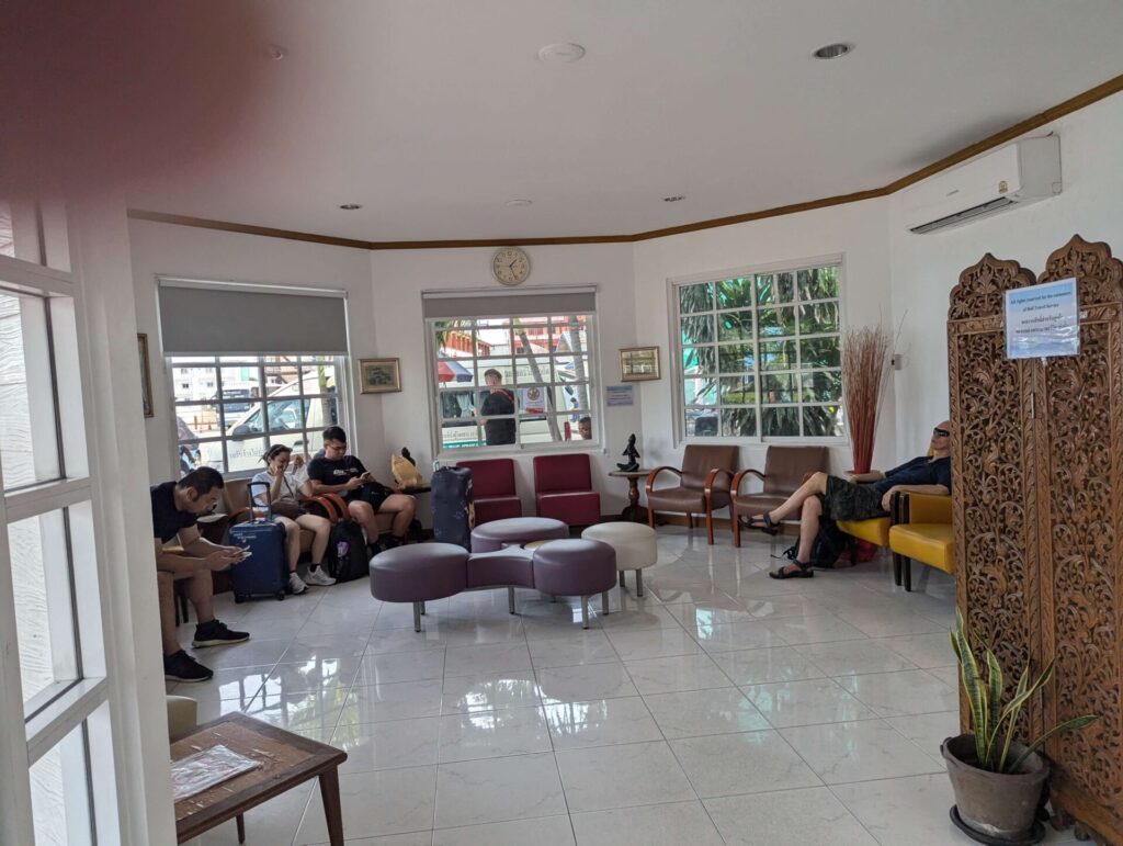 Interior of the Bell Travel Service waiting area with chairs and passengers waiting with their luggage