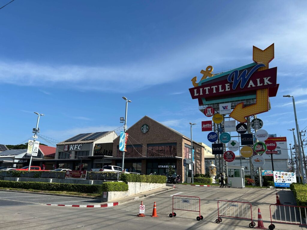 The main entrance of Little Walk Pattaya, an outdoor mall with a large anchor-shaped sign, featuring popular shops like Starbucks and KFC, indicating a convenient stop for travelers near Pattaya bus terminal