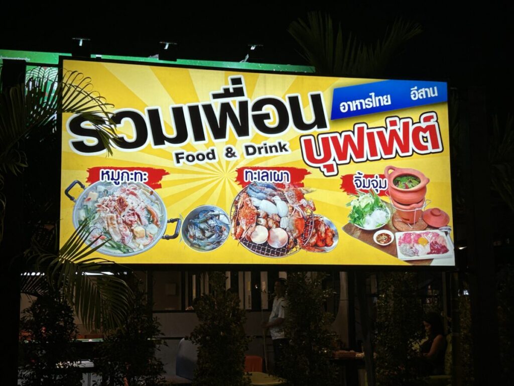 The main signboard for Ruam Phuean Buffet (รวมเพื่อน) showcasing Mookata, Talay Phao (seafood BBQ), and Chim Chum.