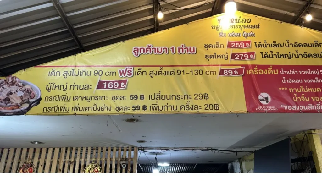 A large yellow banner displaying the menu and pricing for the buffet at Phaa Nong Mookata (ป๋าหน่อง หมูกระทะบุฟเฟ่ต์).