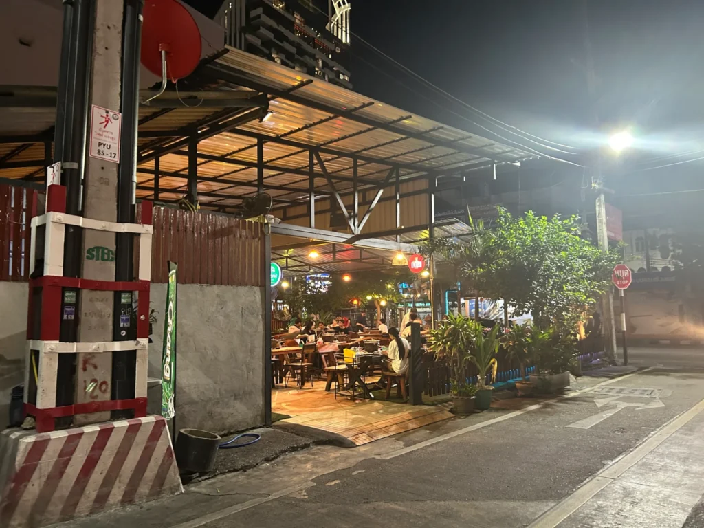 Night exterior view of the open-air Ban Chieng 1 Mookata restaurant on Third Road in Pattaya, showing the entrance and outdoor seating under a metal roof.