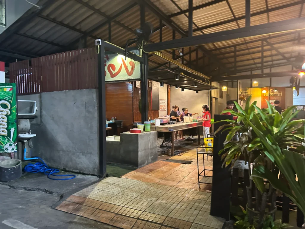 View of the staff and preparation area at the Ban Chieng 1 Mookata restaurant in Pattaya, showing a concrete counter and simple, functional setup.