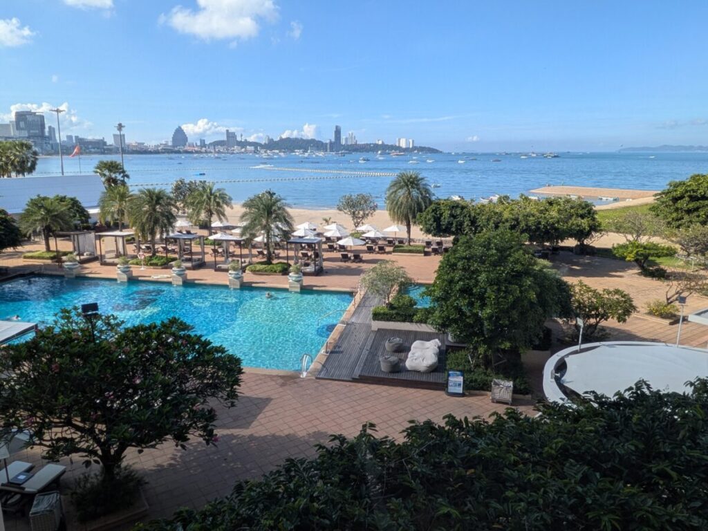 A view of North Pattaya's calm ocean and lush grounds, taken from inside the Dusit Thani Pattaya hotel area during the day.