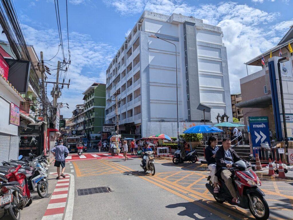 The daytime view of Soi Buakhao near the Sutus Court hotel, showing the calm street with parked motorbikes, low-rise buildings, and commercial signs