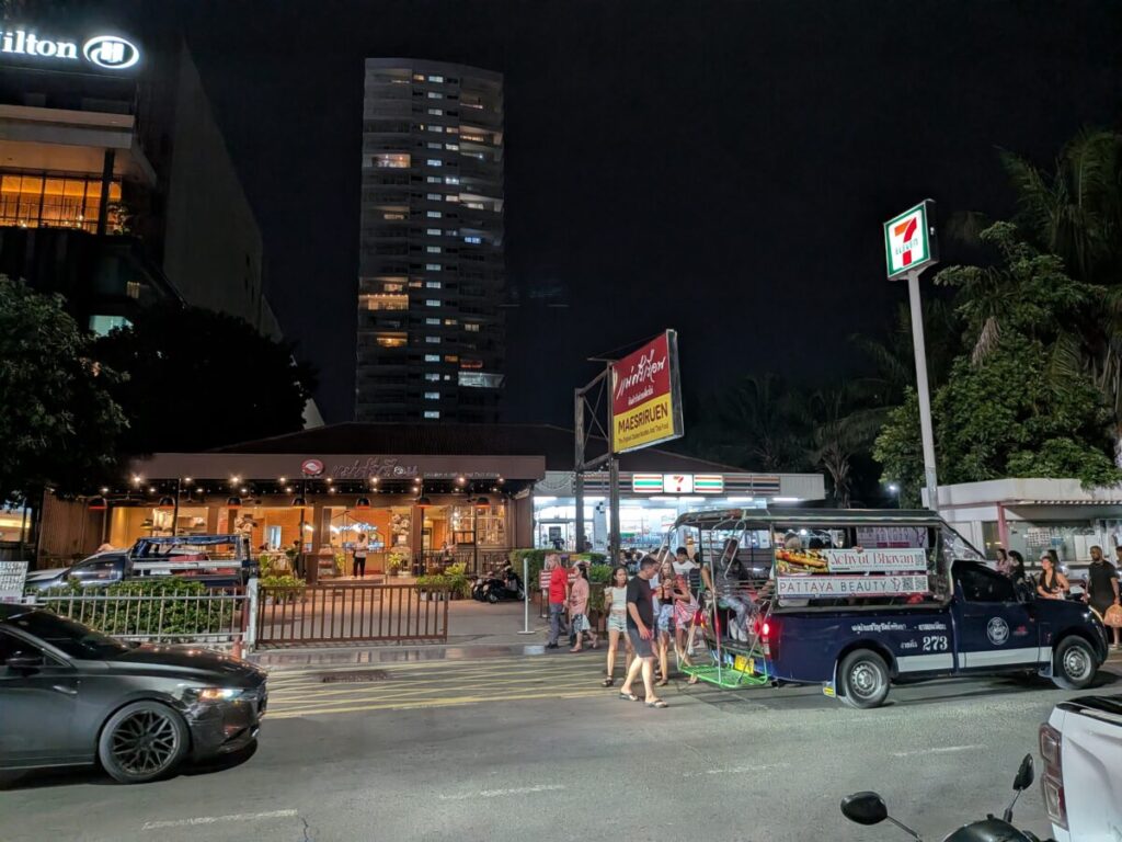 A typical scene on a Pattaya street with hotels in the background, featuring a passing songthaew (local shared taxi) as a key mode of transportation.