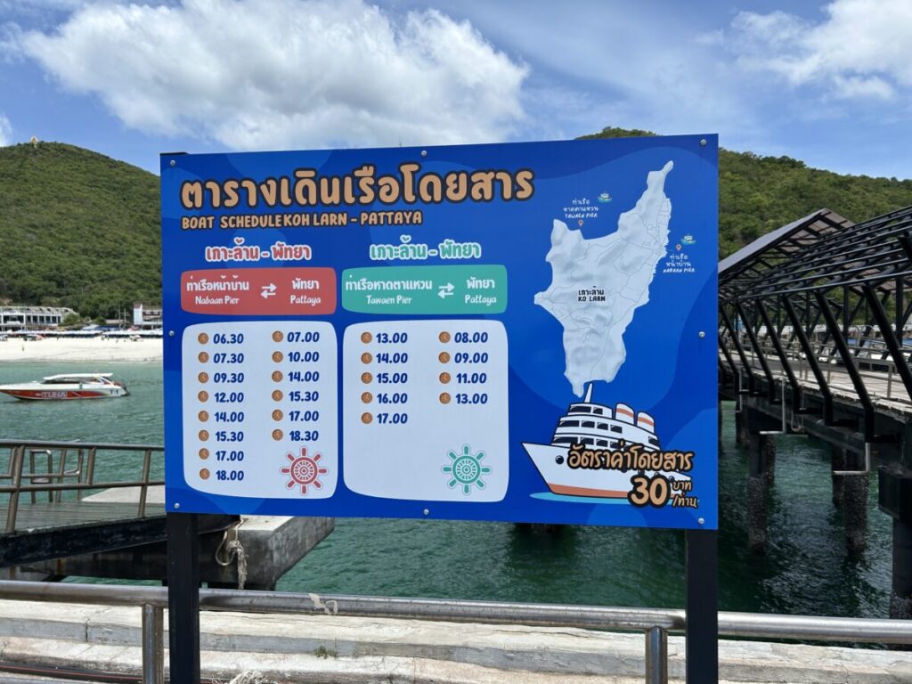 Koh Larn ferry schedule sign at the pier showing boat times