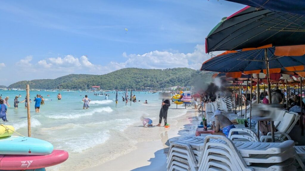 Crowded zone at Tawaen Beach with colorful parasols, beach chairs, and tourists enjoying the water.