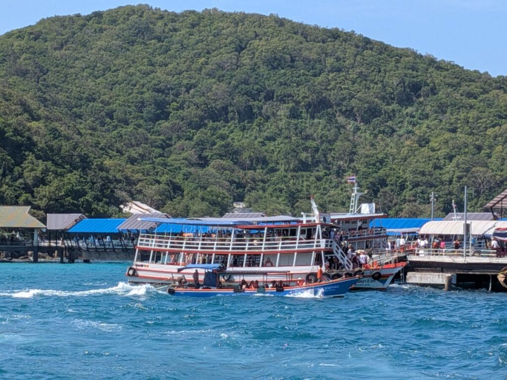 Tawaen Beach Pier upon arrival, showing the vibrant atmosphere and clear water.