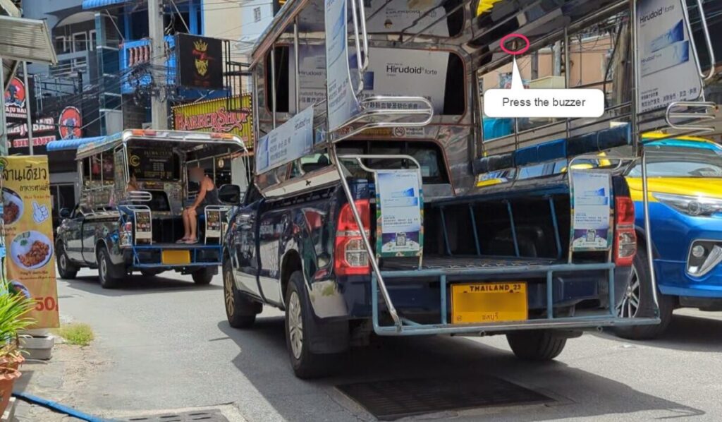 Passenger pressing the buzzer inside a Pattaya songthaew to signal getting off