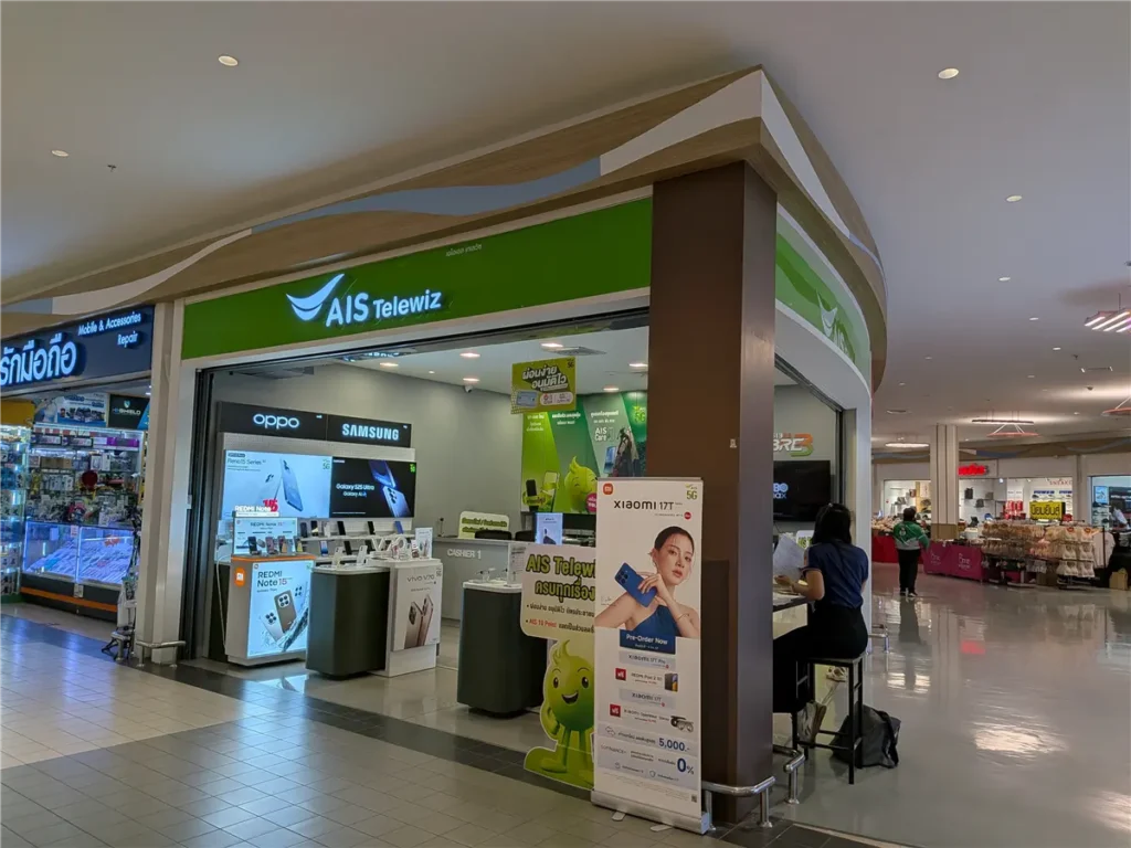 A traveler sitting at an authorized AIS mobile service counter in Pattaya for SIM card registration.