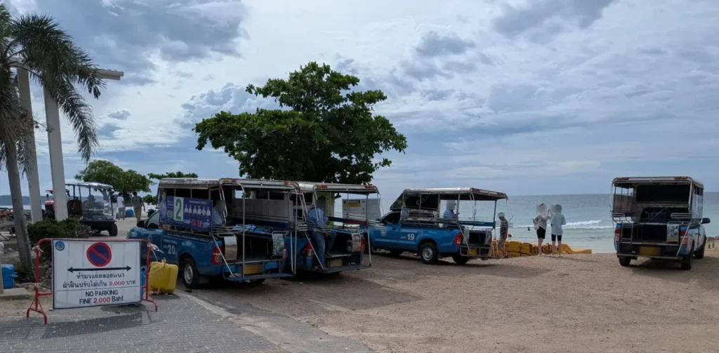 Blue songthaews parked at the designated pick-up and waiting area at Tien Beach, Koh Larn.