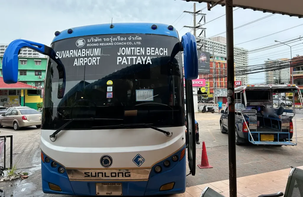 A Roong Reuang Coach bus displaying Suvarnabhumi Airport and Jomtien Beach Pattaya at the Jomtien bus stop.