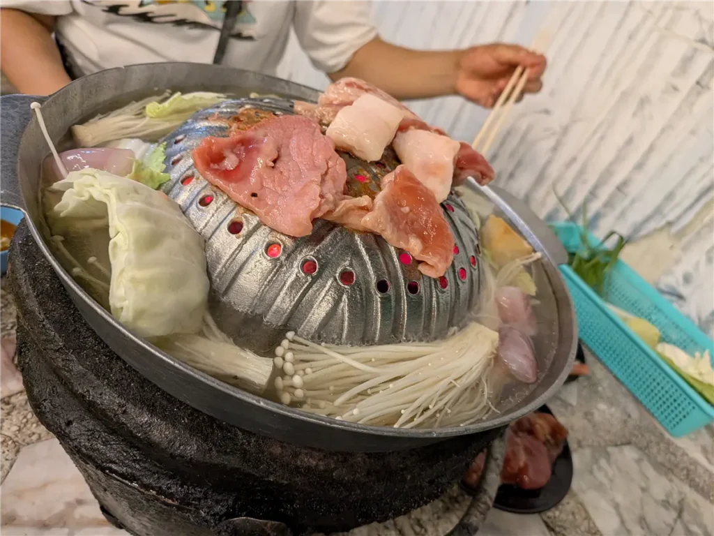 Mookata pan with meat grilling on the raised dome and broth cooking around it