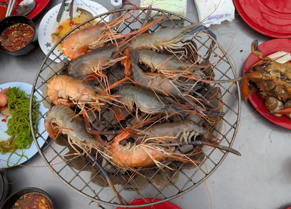 Seafood being grilled on a wire grill at a Mookata meal